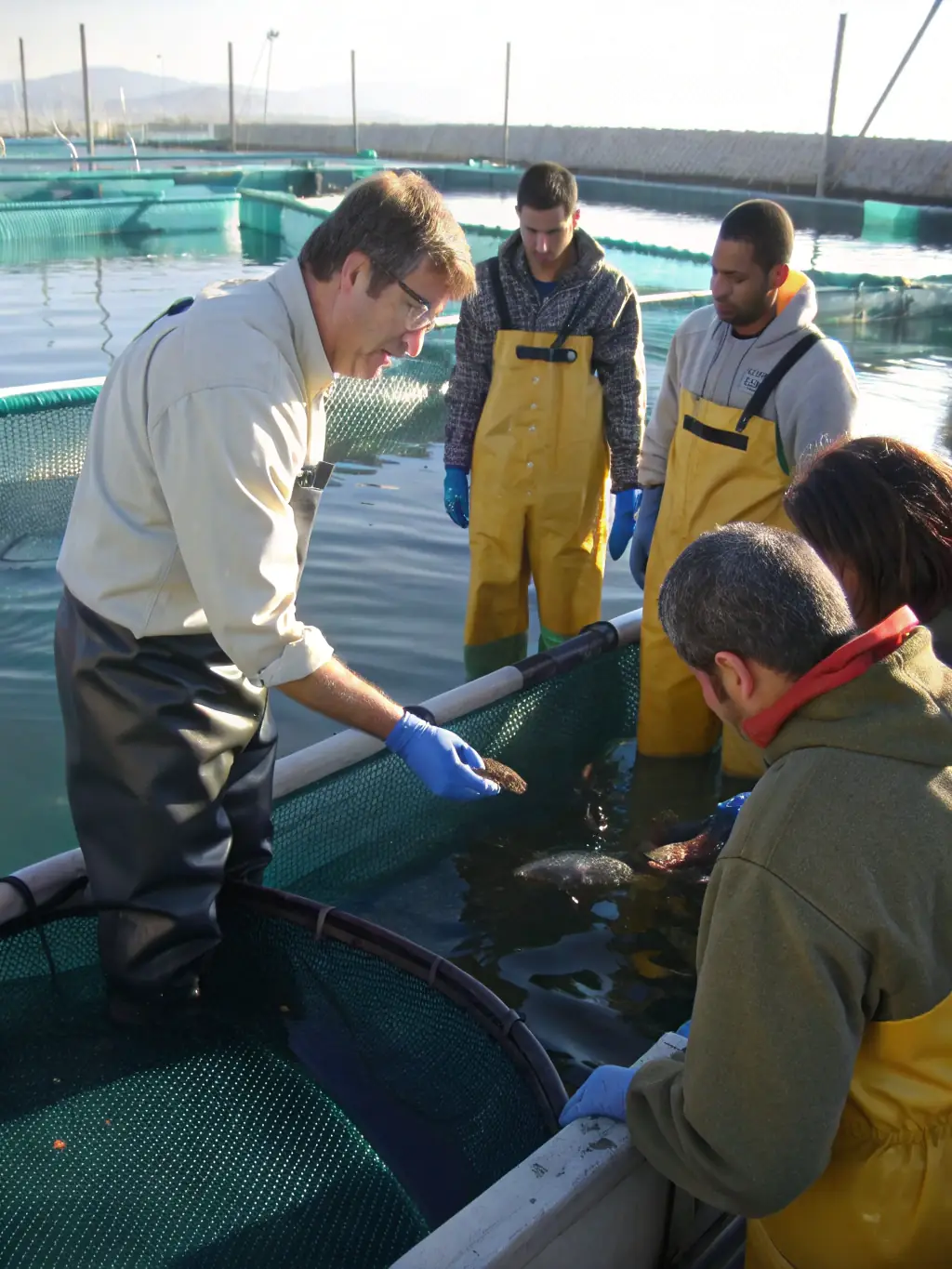 An image of a workshop where participants are learning about sustainable fishing practices, including proper catch and release techniques. The instructor is demonstrating the correct way to handle a fish, emphasizing the importance of minimizing harm to the animal.